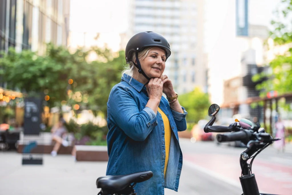 senior woman putting on helmet before riding e-bike